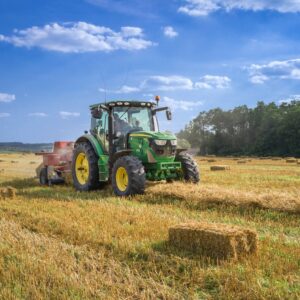 green tractor on brown grass field under blue sky during daytime